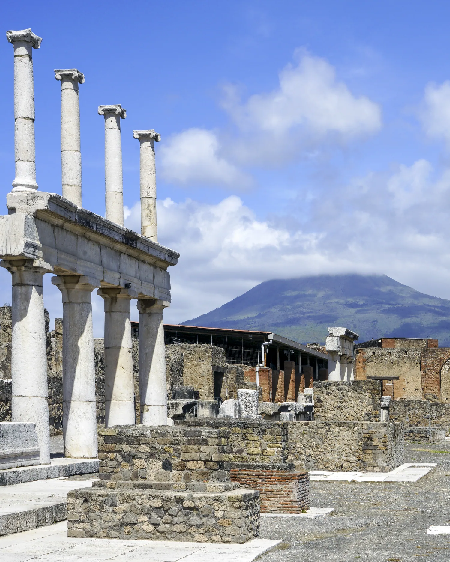 Il colonnato del Foro di Pompei con il Vesuvio sullo sfondo, sotto un cielo di cumuli
